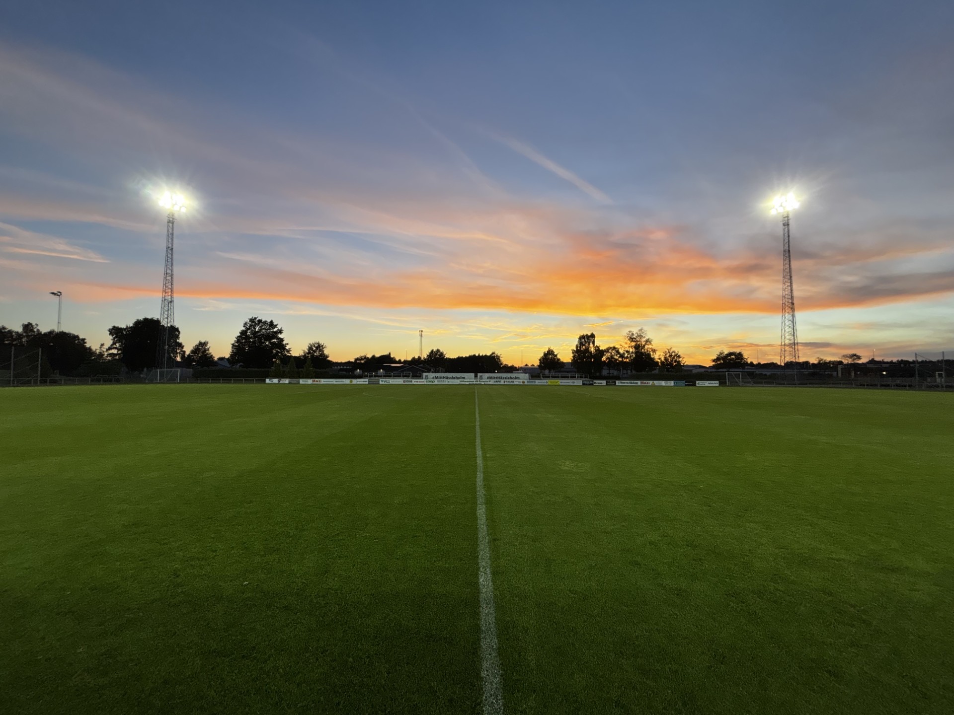 Crossberry floodlights on lattice masts illuminating a football pitch at dusk