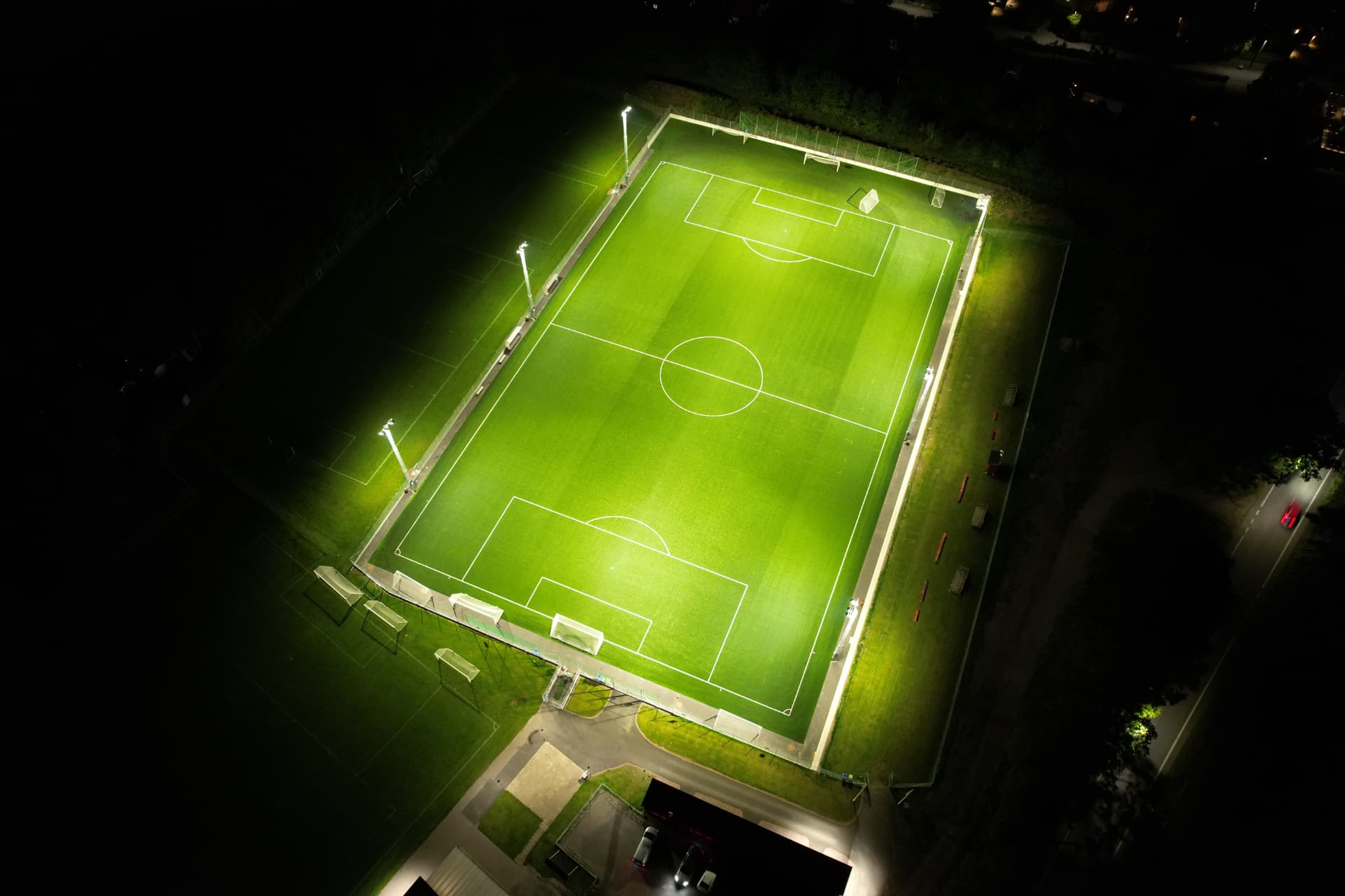 Aerial night view of a football pitch illuminated by Crossberry floodlights on lattice masts