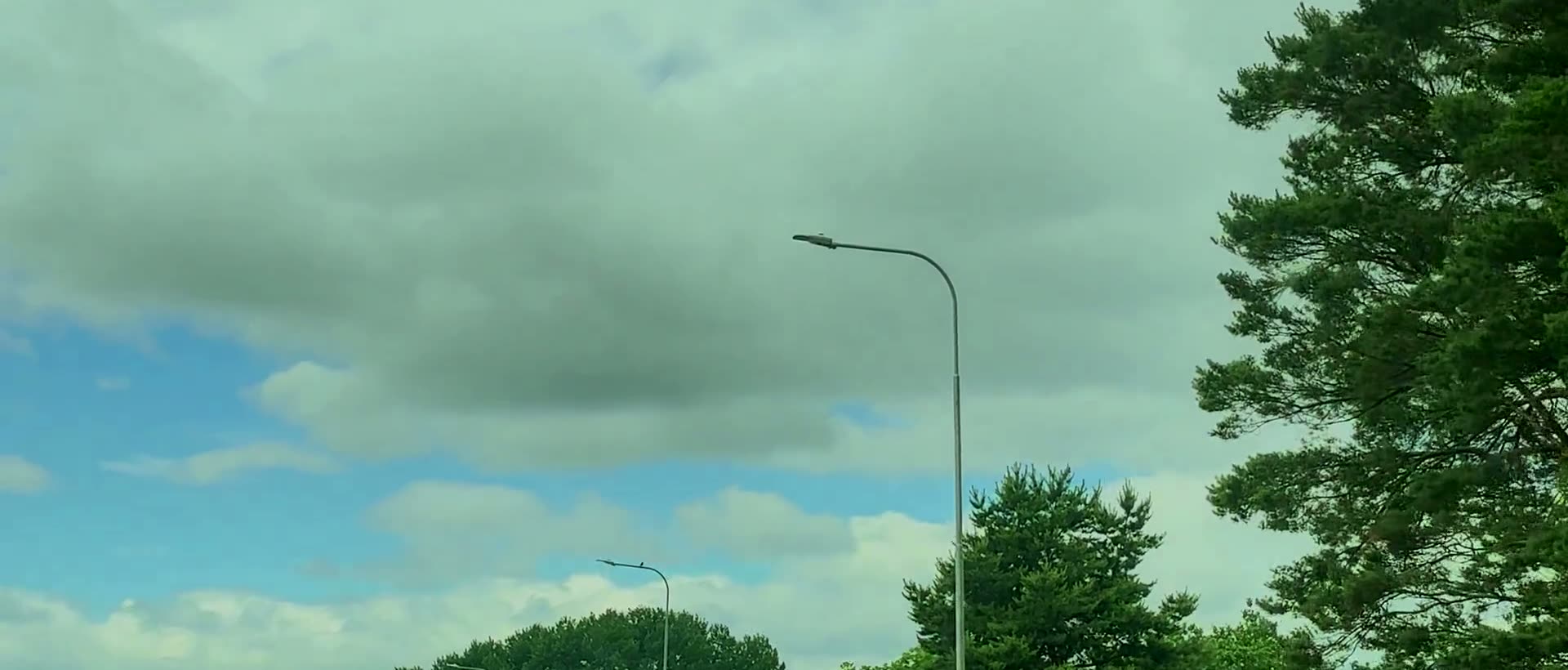 Road lighting column with a Crossberry luminaire against a summer sky